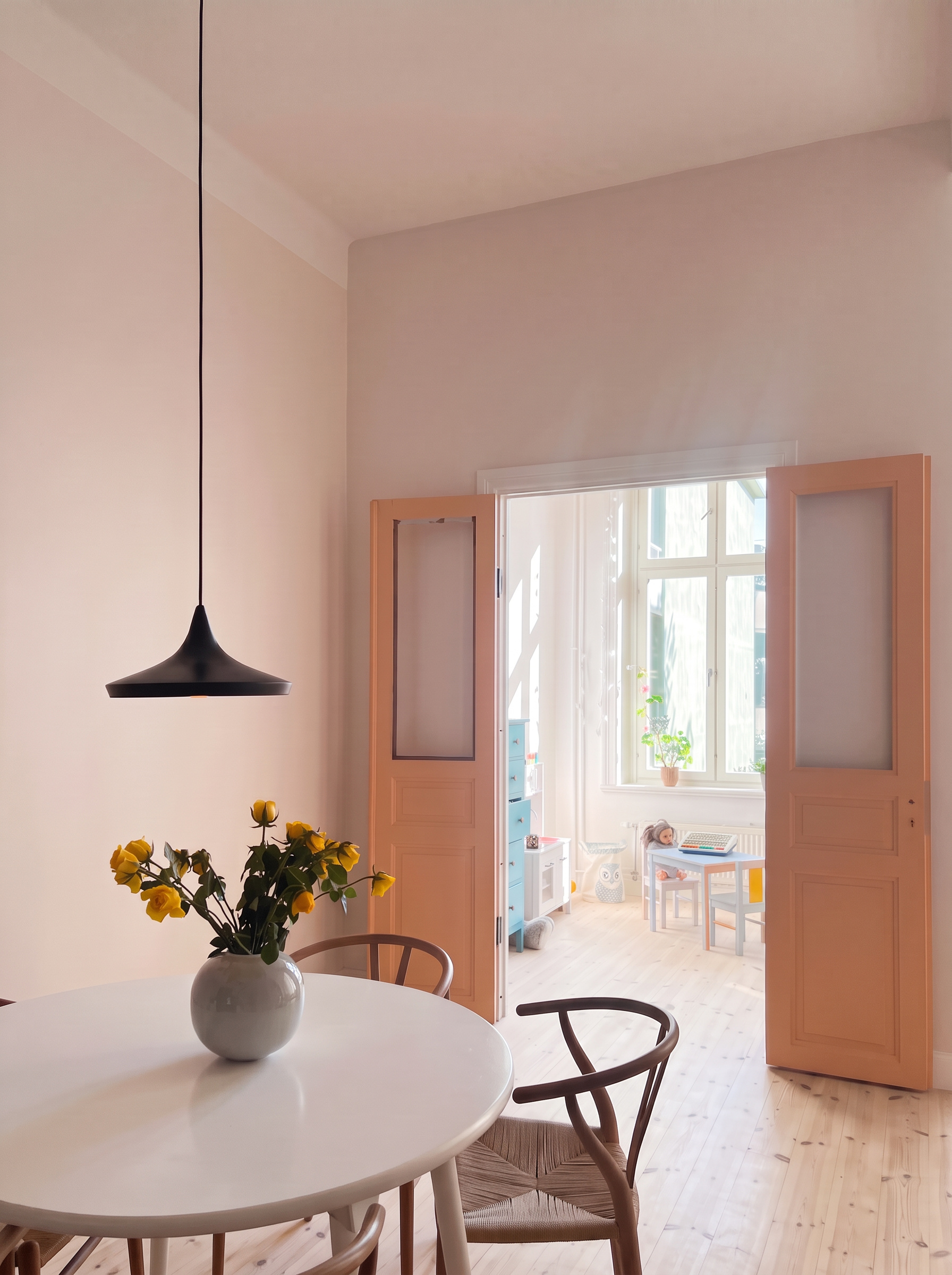 Runt vitt matbord med gula rosor och svart taklampa i varmt beige rum